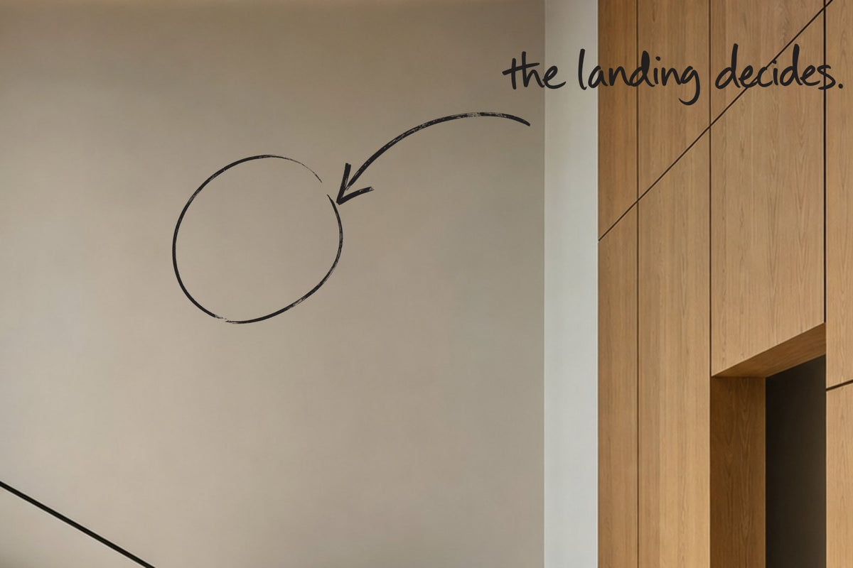 A stair landing in a coastal loft, a steel-framed window beside the travertine treads, the wall above the landing circled in open black marker, an arrow from the handwritten words the landing decides, by Willem van der Krieken