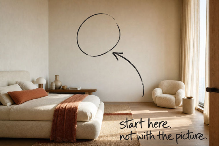 A contemporary bedroom in daylight, a low upholstered bed along one wall, the empty wall circled in open black marker, an arrow from the handwritten words start here, not with the picture, by Willem van der Krieken