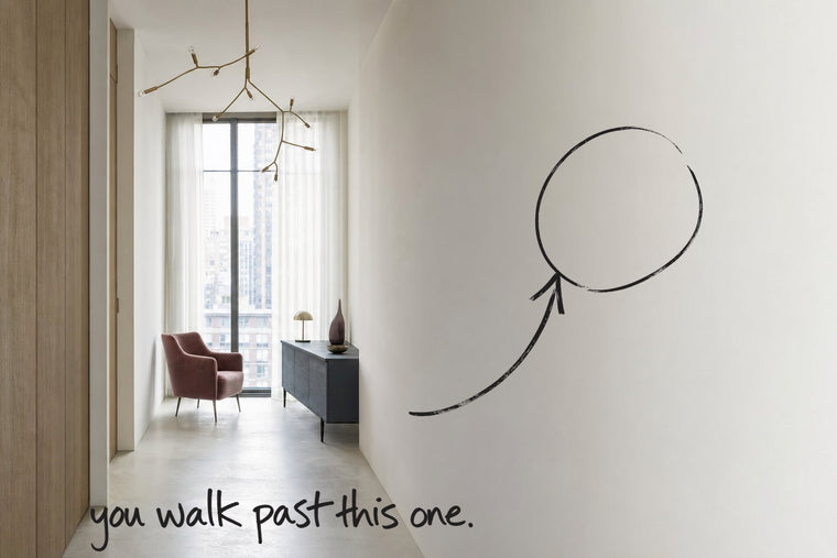 A narrow entrance hall in a bright apartment, a tall window with slim black frames at its end, the near wall circled in open black marker, an arrow from the handwritten words you walk past this one, by Willem van der Krieken