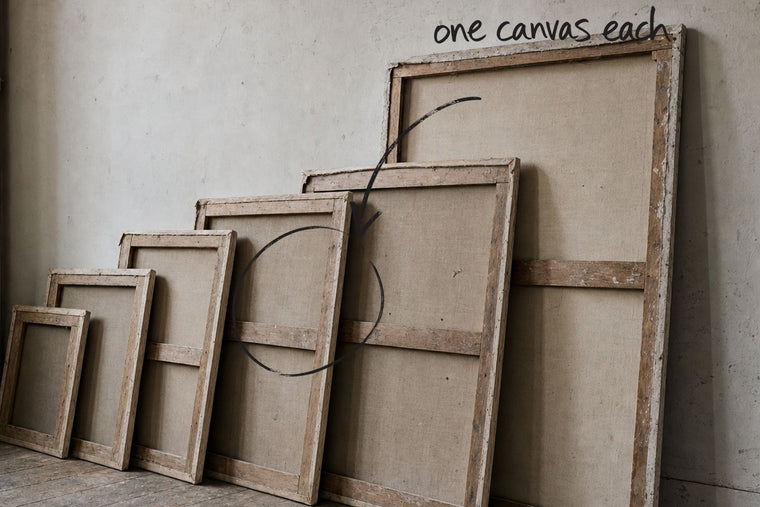 Five stretched canvases of different sizes standing in a row, all turned face to the wall, one canvas in the row circled in open black marker, an arrow from the handwritten words one canvas each, by Willem van der Krieken