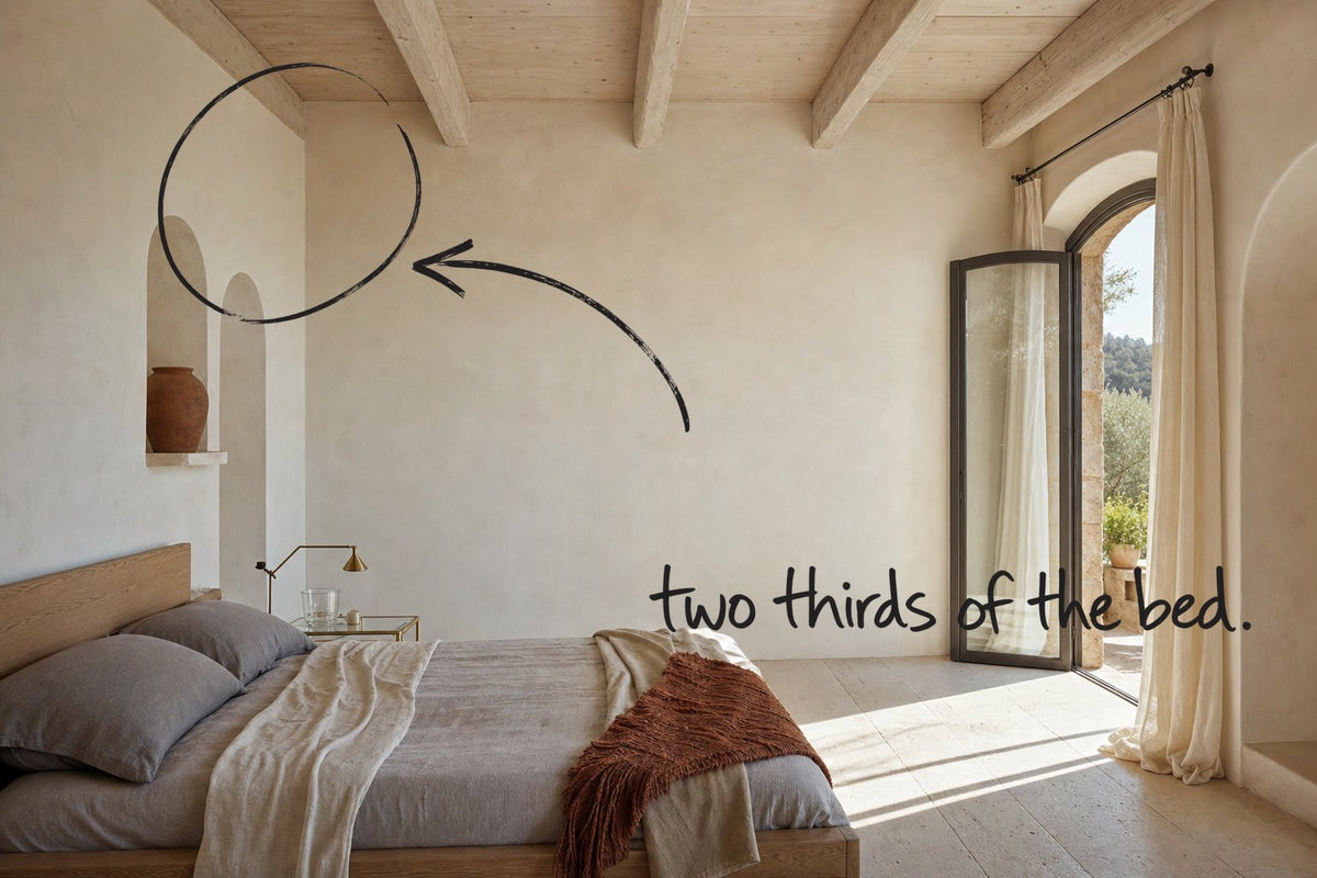 A Mediterranean bedroom with pale ceiling beams and arched plaster niches, the wall above the headboard circled in open black marker, an arrow from the handwritten words two thirds of the bed, by Willem van der Krieken