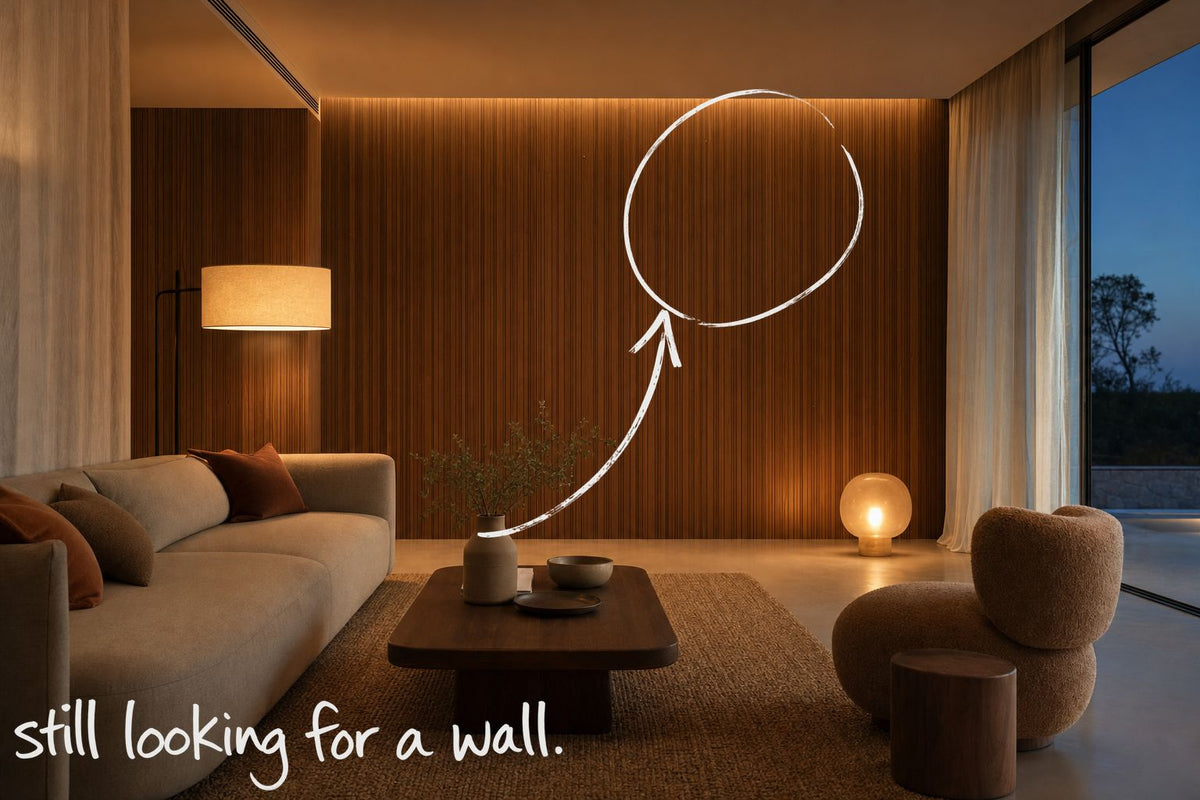 A contemporary living room at dusk, lamplight across a walnut slatted wall, the empty wall circled in open black marker, a marker arrow running to it from the handwritten words still looking for a wall, by Willem van der Krieken